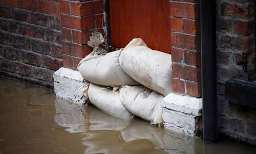 A doorway with sandbags piled on top of it to hold back flood waters.
