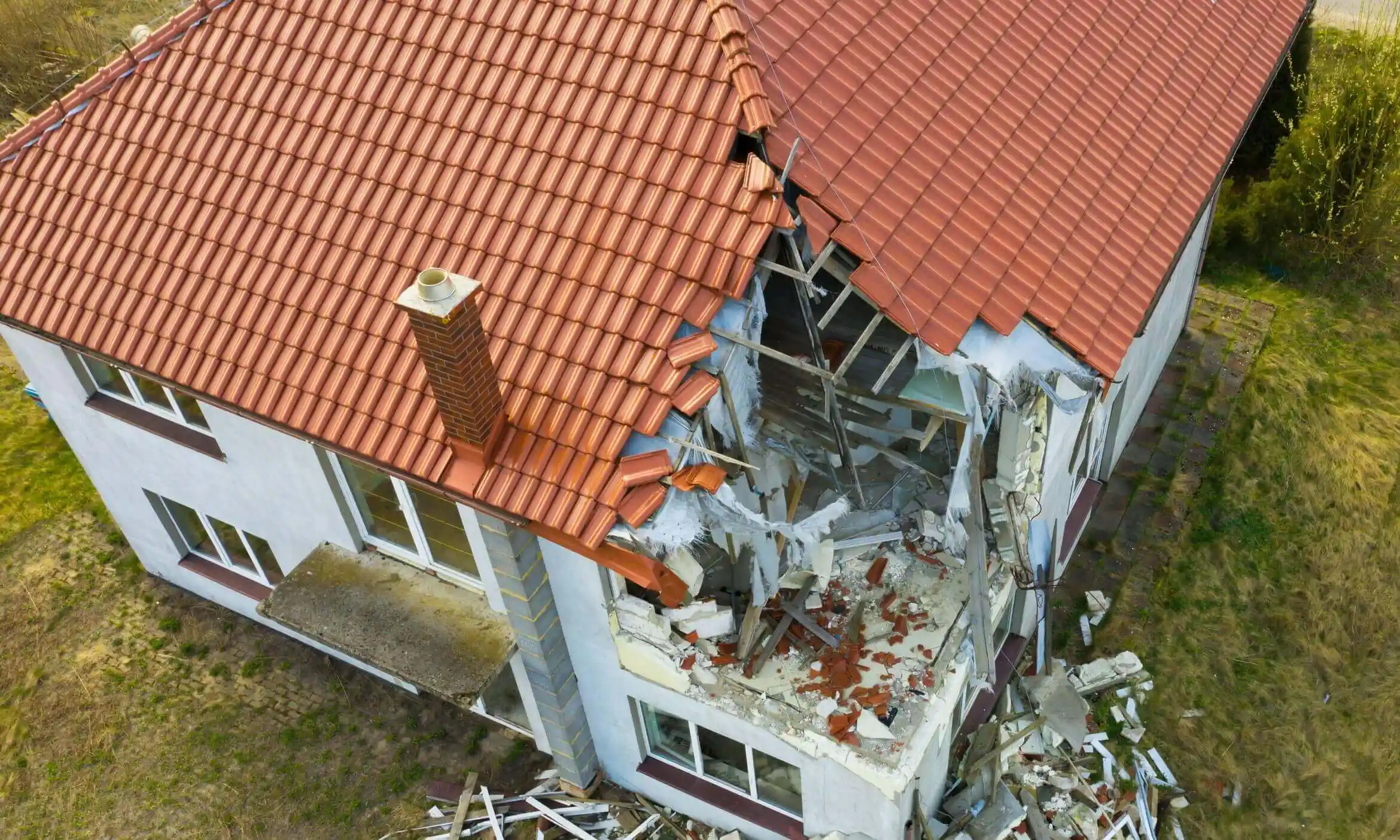 An aerial shot of a red shingle roof house damaged by a storm.