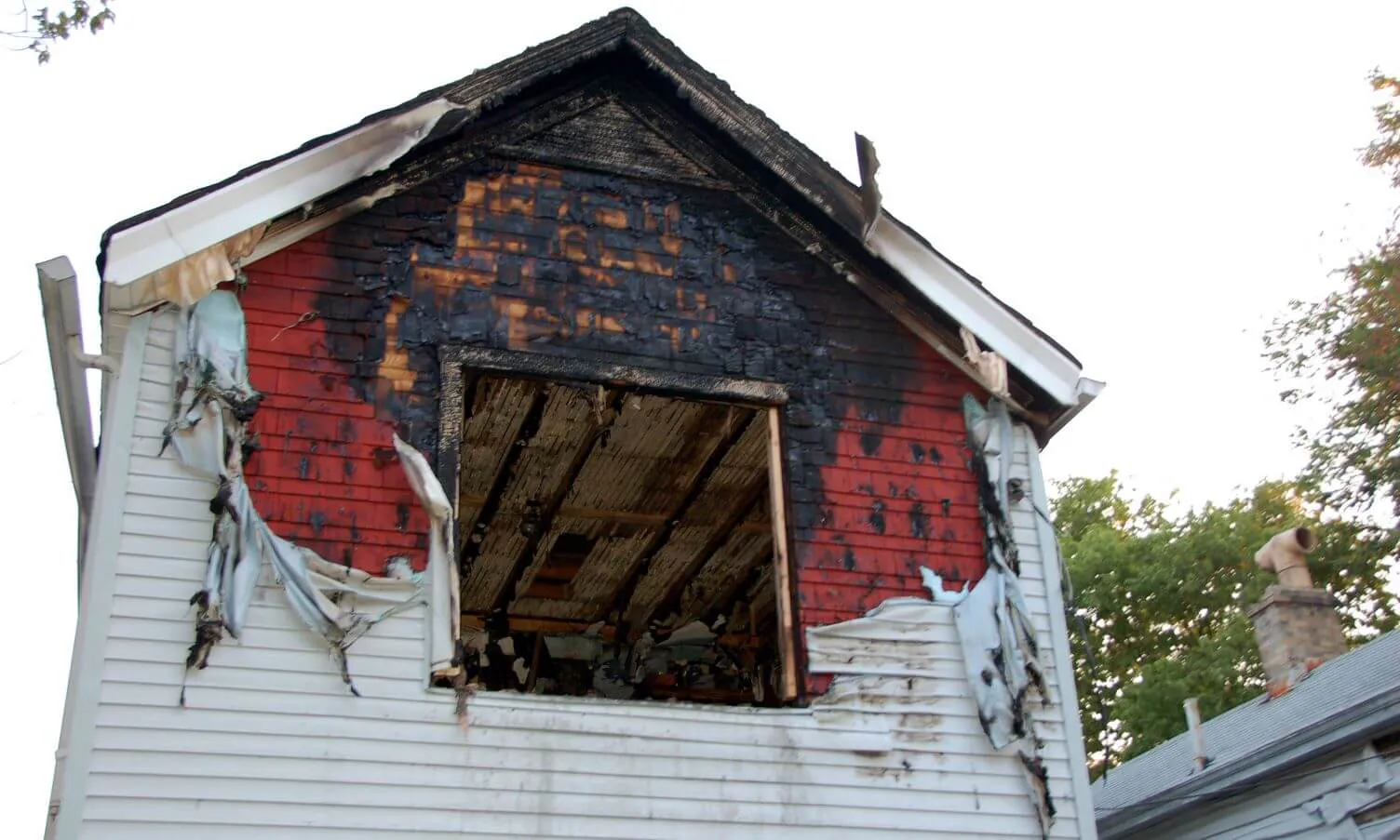 A shot of a dormer of a Floridian house with fire and smoke damage and peeled off paint.